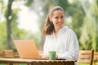 Handsome Young Woman Enjoys Working Outdoors At A Cafe Terrace In A Park