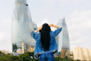 Long Haired Brunette Girl Travels On Vacation Posing Against A Background Of Modern Buildings