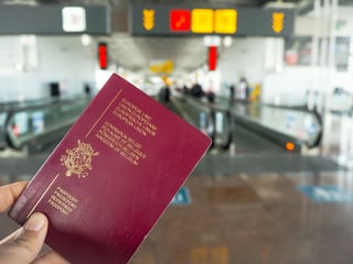 Person Holding A Belgian Passport While Walking In A Airport Terminal