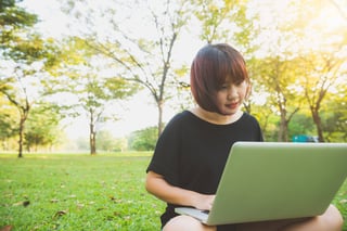 young asian womans legs on the green grass with open laptop girls hands on keyboard young asian womans legs on the green grass with open laptop girls hands on keyboard