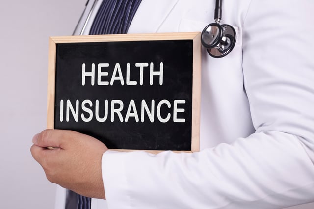 Un m&eacute;dico sosteniendo un cartel de seguro m&eacute;dico