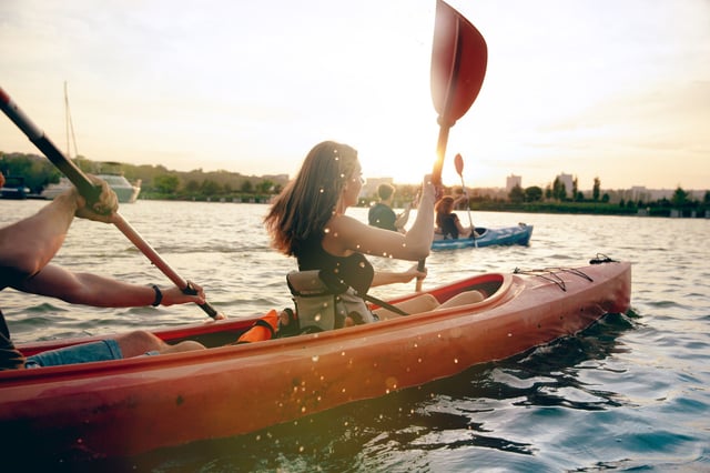 Amigos haciendo kayak en el r&iacute;o al atardecer