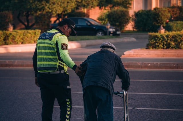 Polic&iacute;a ayudando a un hombre mayor a cruzar la calle