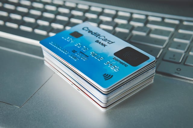 Pila de tarjetas de cr&eacute;dito en una computadora port&aacute;til