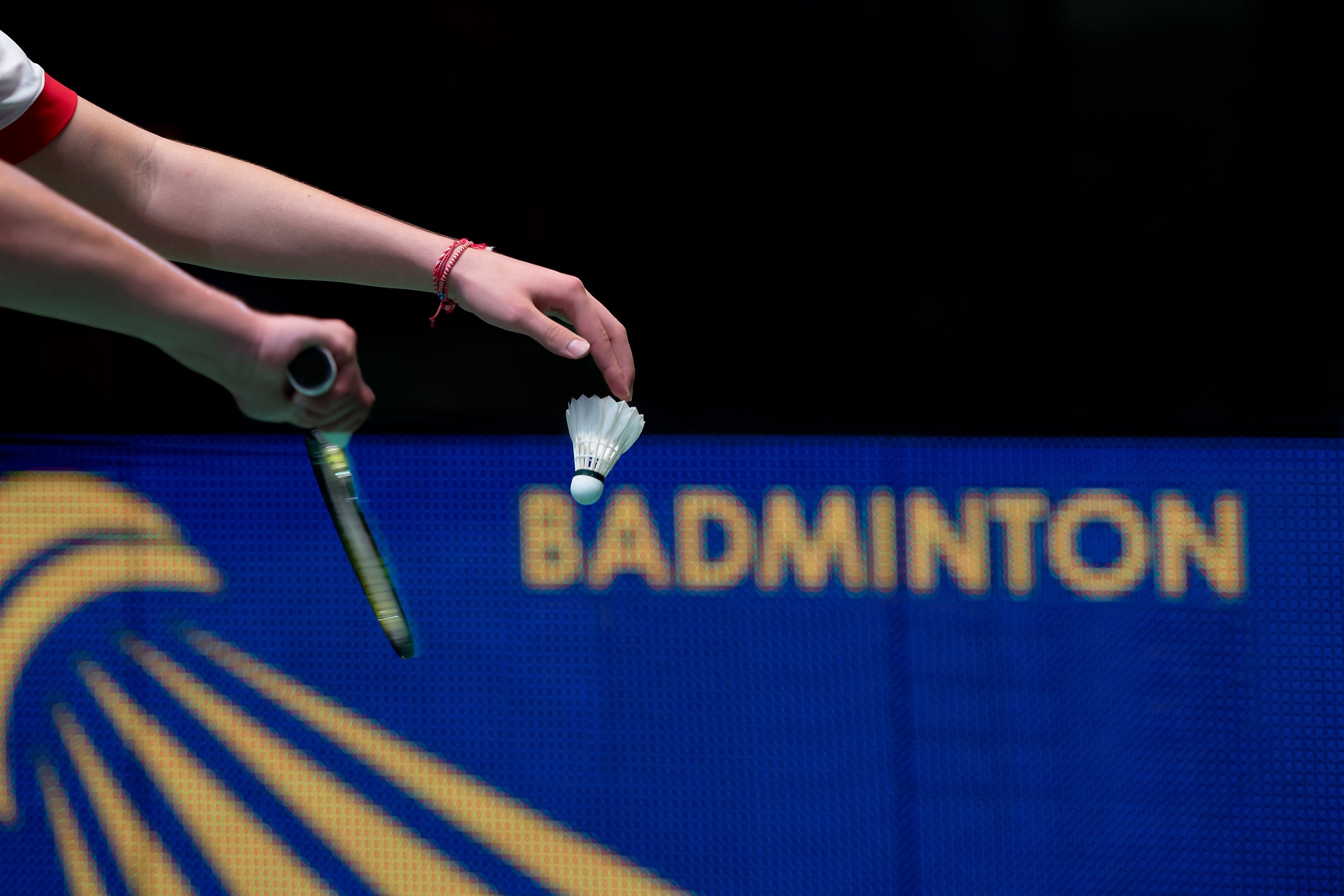 Hand eines Badmintonspielers mit Schl&auml;ger und Federball