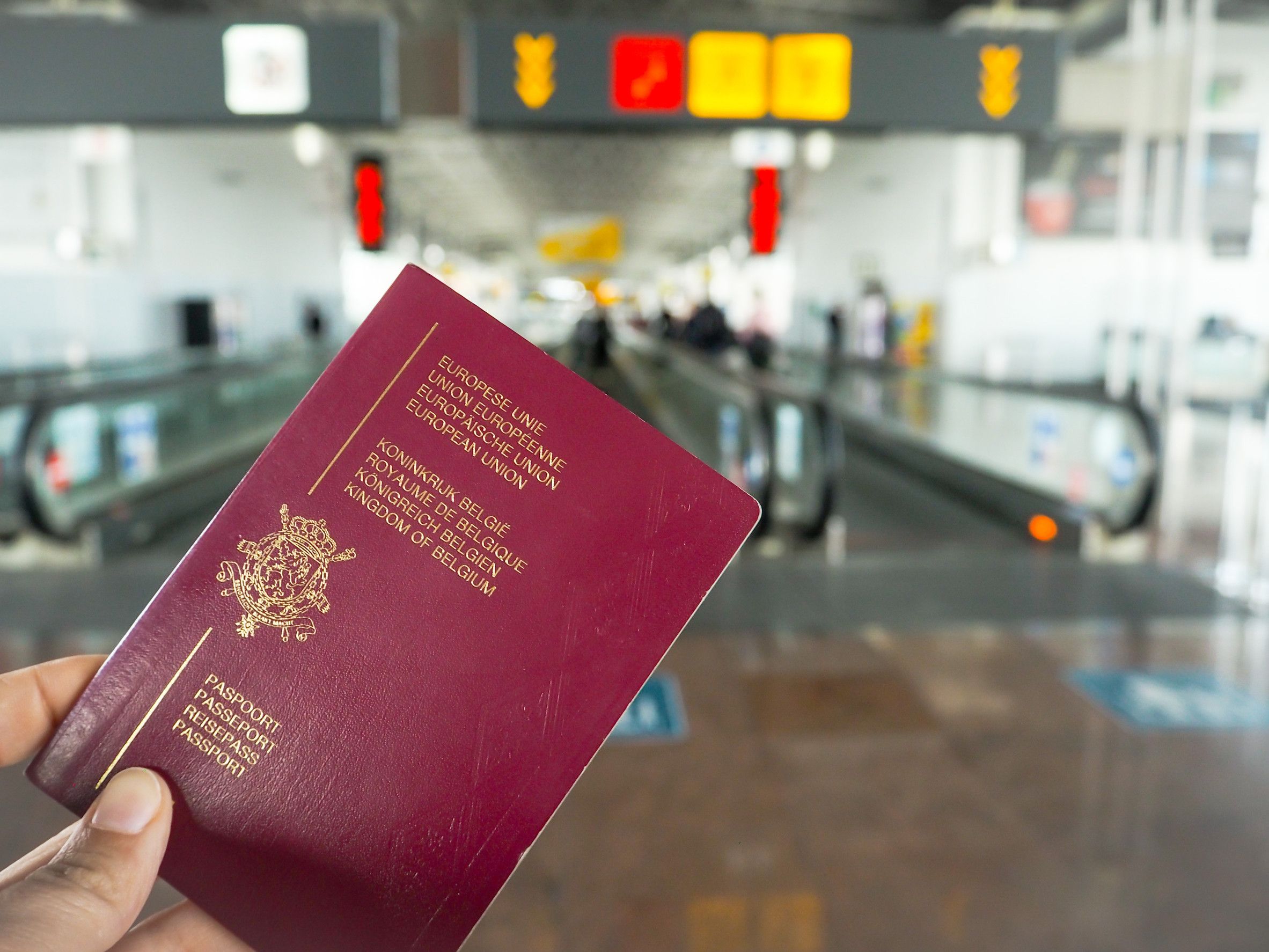 Persona in possesso di passaporto belga mentre cammina nel terminal di un aeroporto
